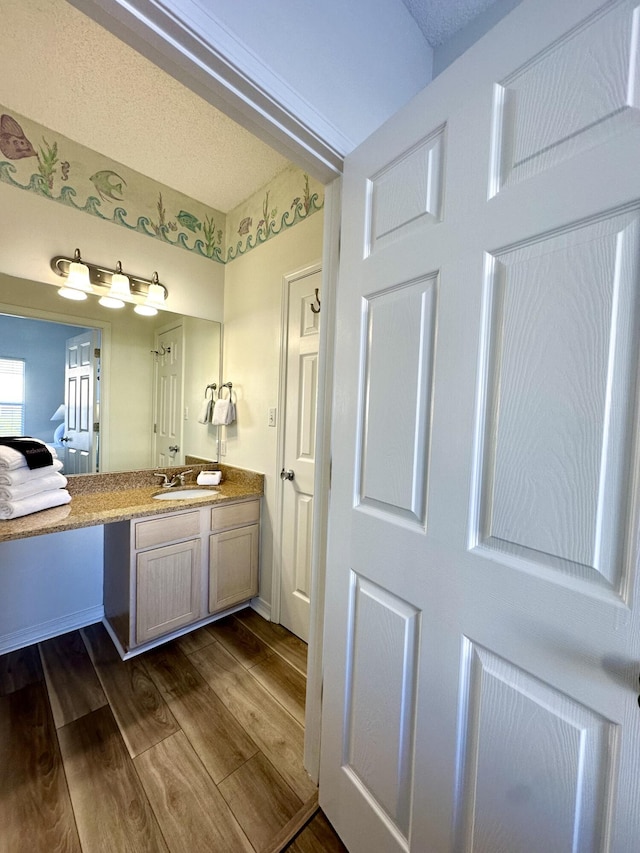 bathroom with vanity, wood-type flooring, and a textured ceiling