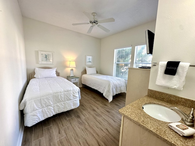 bedroom featuring hardwood / wood-style flooring, ceiling fan, and sink