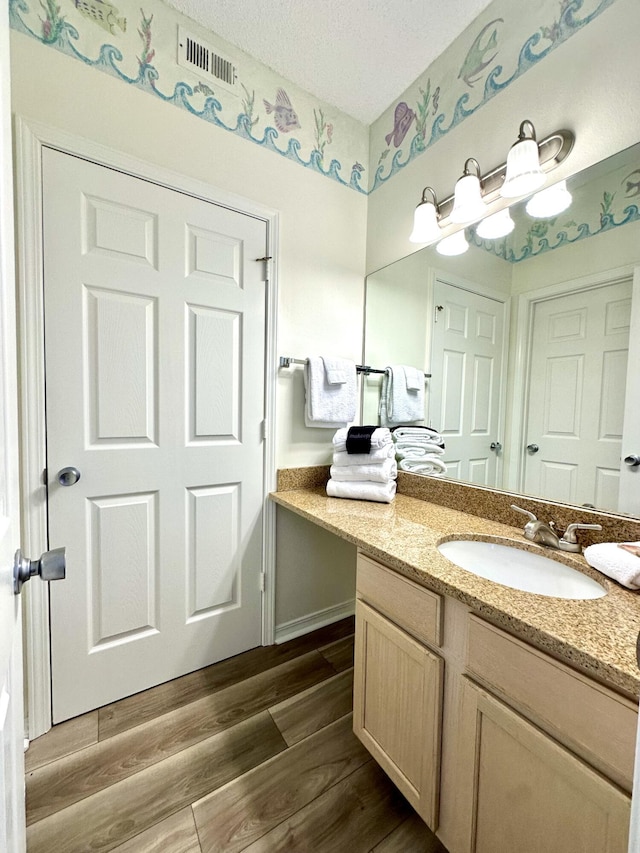 bathroom with a textured ceiling, vanity, and hardwood / wood-style flooring