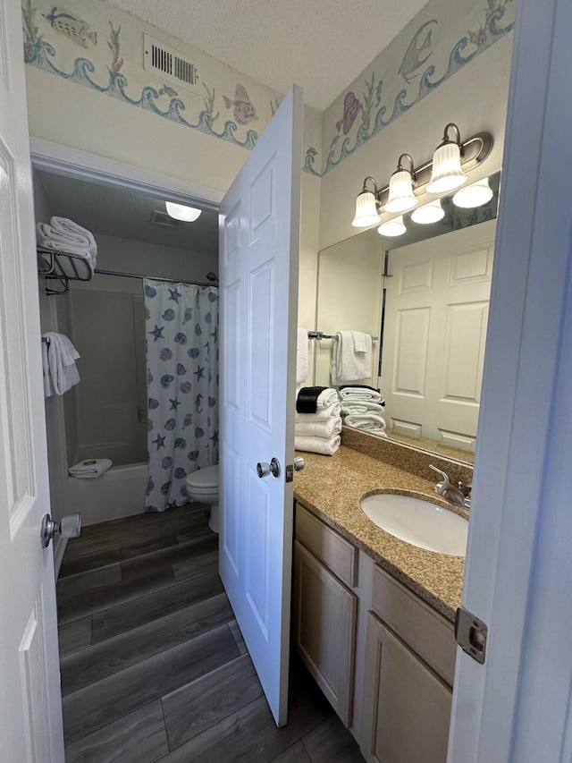 full bathroom featuring vanity, toilet, shower / bathtub combination with curtain, a textured ceiling, and wood-type flooring