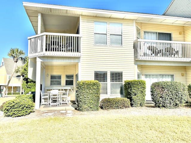 rear view of property with a patio area, a yard, and a balcony