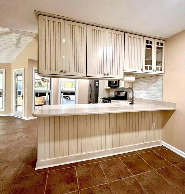 kitchen featuring backsplash, cream cabinets, sink, and stainless steel appliances