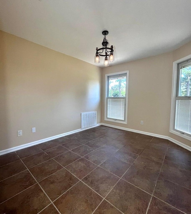 tiled empty room featuring a notable chandelier