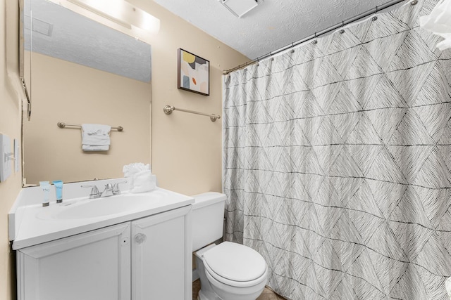 bathroom featuring curtained shower, vanity, a textured ceiling, and toilet