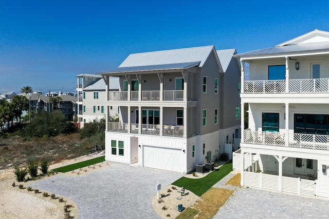 view of front facade with a balcony, a garage, and central air condition unit