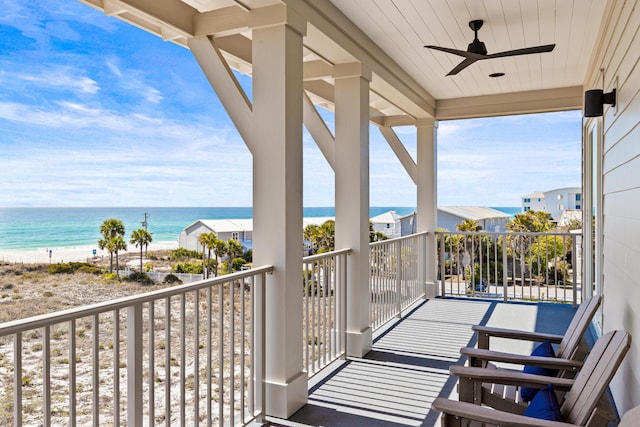 balcony featuring a view of the beach, ceiling fan, and a water view