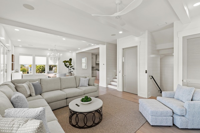 living room with beamed ceiling, ceiling fan with notable chandelier, and light wood-type flooring