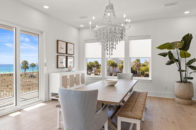 dining room featuring a water view, a healthy amount of sunlight, and light wood-type flooring