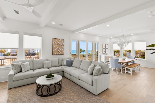 living room with ceiling fan with notable chandelier, light hardwood / wood-style floors, and beamed ceiling