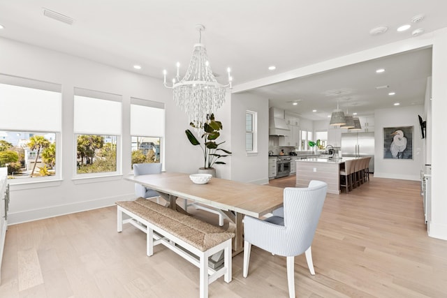 dining room featuring sink, a chandelier, and light wood-type flooring