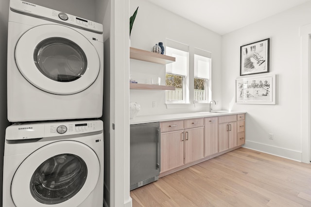 laundry area featuring sink, light hardwood / wood-style floors, and stacked washer / dryer