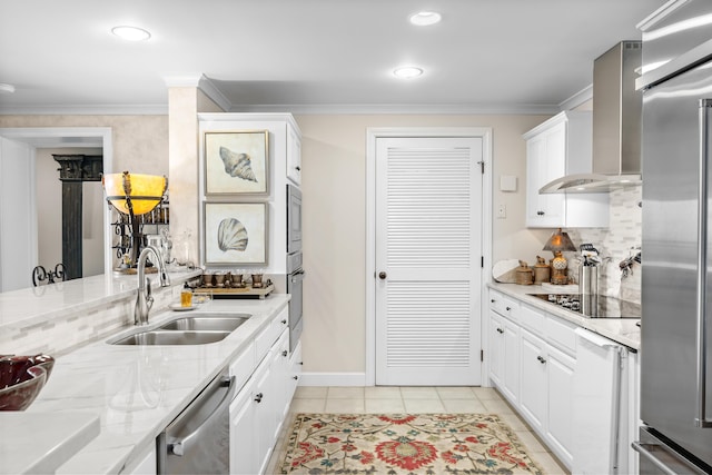 kitchen featuring light stone counters, wall chimney exhaust hood, sink, built in appliances, and white cabinets