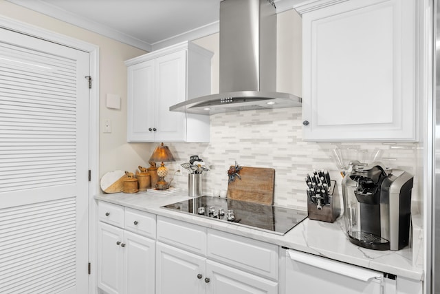 kitchen featuring black electric stovetop, crown molding, wall chimney exhaust hood, tasteful backsplash, and white cabinetry