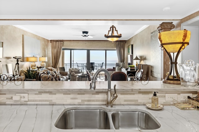 kitchen with light stone counters, sink, ceiling fan, and ornamental molding