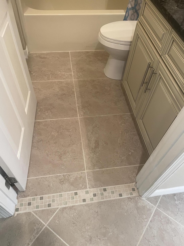 bathroom with a bathing tub, tile patterned flooring, and toilet