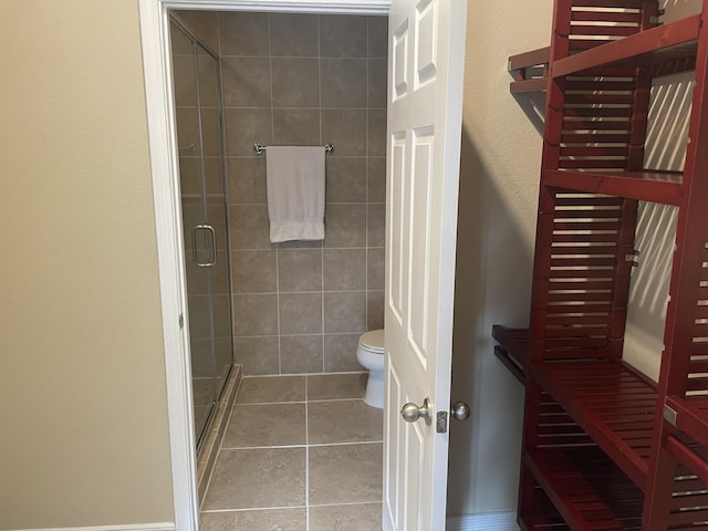 bathroom with tile patterned flooring, a shower with door, and toilet