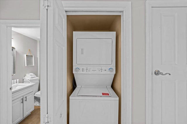 washroom featuring stacked washer and dryer and light tile patterned flooring