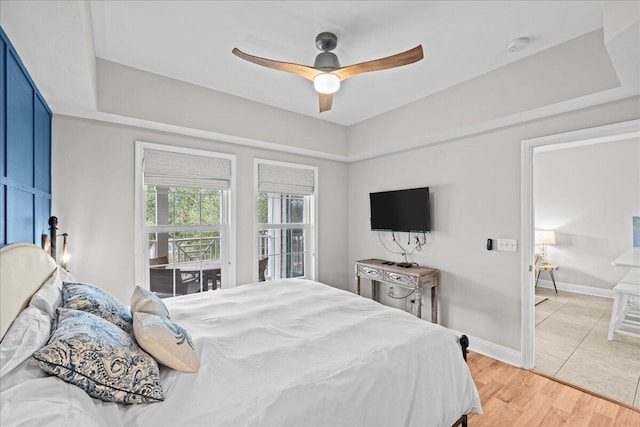 bedroom with wood-type flooring, a raised ceiling, and ceiling fan