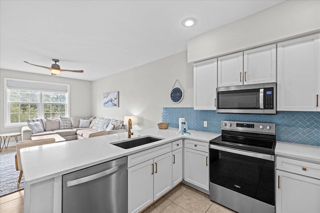 kitchen with kitchen peninsula, appliances with stainless steel finishes, decorative backsplash, sink, and white cabinetry