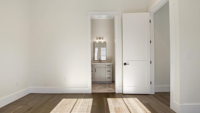 unfurnished bedroom featuring sink, dark wood-type flooring, and ensuite bath