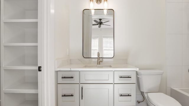 bathroom featuring built in shelves, ceiling fan, a washtub, toilet, and vanity