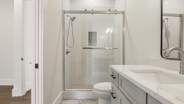 bathroom with vanity, a shower with shower door, and toilet