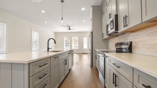 kitchen with stainless steel appliances, ceiling fan, gray cabinetry, and sink