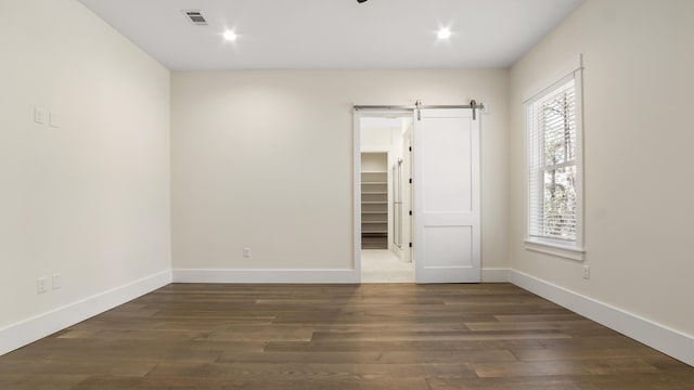 spare room featuring a barn door, dark hardwood / wood-style floors, and a wealth of natural light