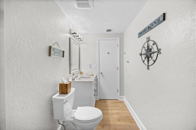 bathroom with hardwood / wood-style floors, vanity, a textured ceiling, and toilet