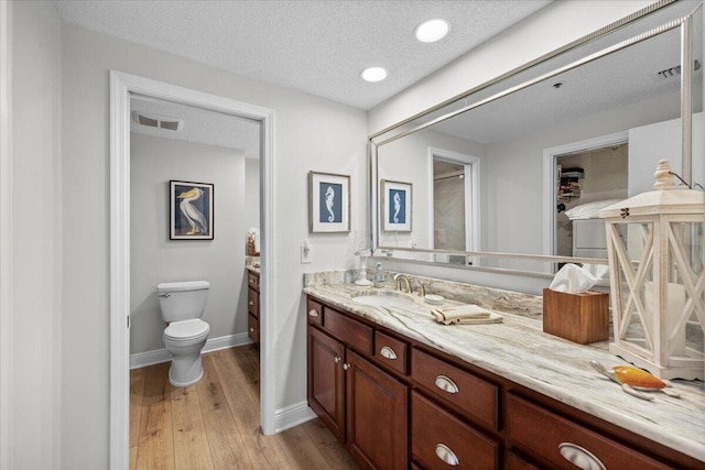 bathroom with toilet, vanity, a textured ceiling, and hardwood / wood-style flooring