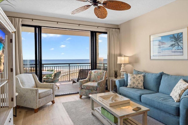 living room featuring a wealth of natural light, a water view, light hardwood / wood-style floors, and a textured ceiling