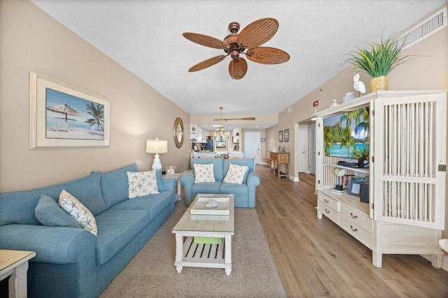 living room featuring ceiling fan, a textured ceiling, and light hardwood / wood-style flooring