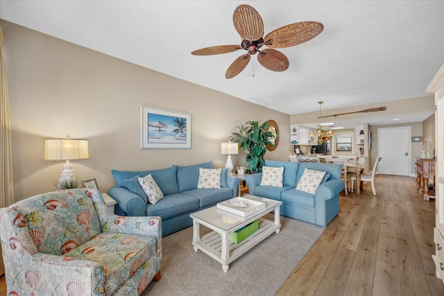 living room with ceiling fan, light hardwood / wood-style flooring, and a textured ceiling