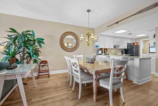 dining space with light hardwood / wood-style flooring, a chandelier, and a textured ceiling