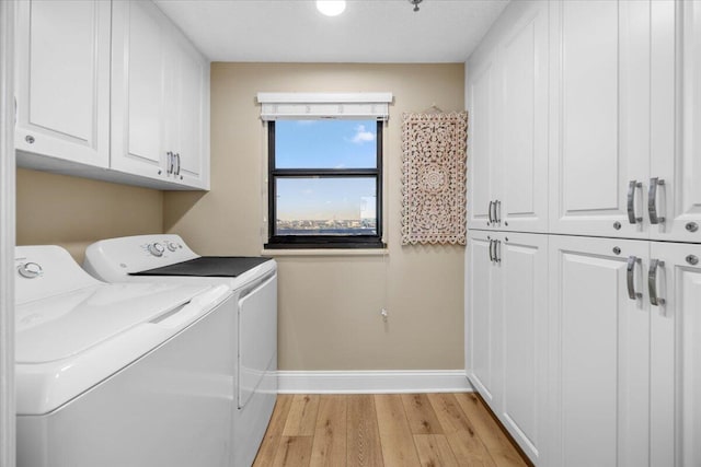 laundry area with cabinets, light hardwood / wood-style floors, and washing machine and clothes dryer