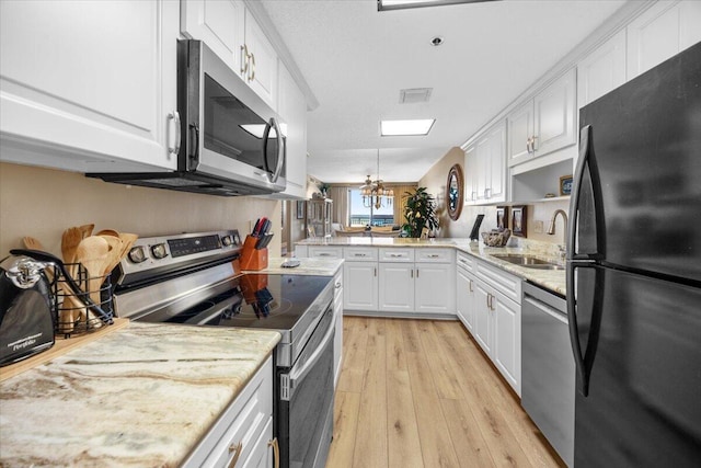 kitchen with appliances with stainless steel finishes, sink, a notable chandelier, light hardwood / wood-style floors, and white cabinetry