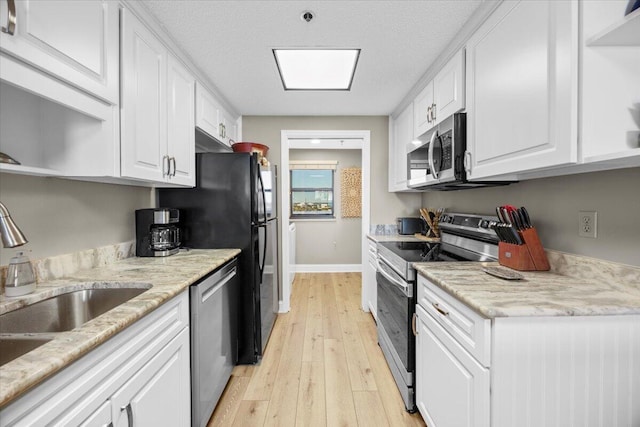 kitchen featuring appliances with stainless steel finishes, light hardwood / wood-style flooring, white cabinetry, and sink