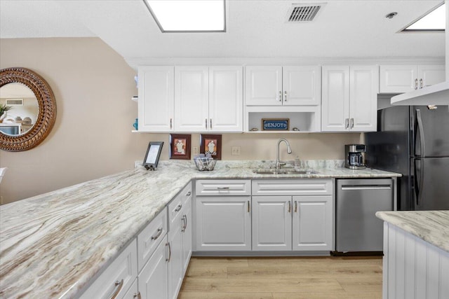 kitchen featuring light stone countertops, sink, stainless steel dishwasher, black refrigerator, and white cabinets