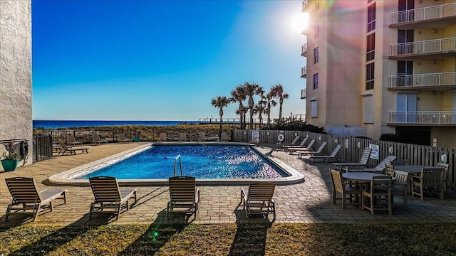 view of swimming pool featuring a water view and a patio