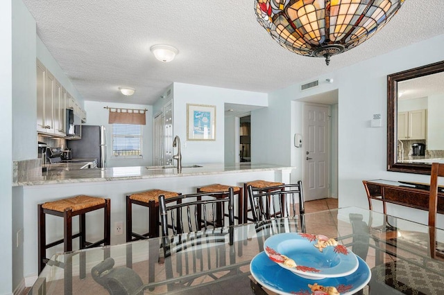 9815 US Highway 98 W Unit 1602, Miramar Beach, FL 32550 - kitchen with a kitchen breakfast bar, a peninsula, stainless steel microwave, a textured ceiling, and range