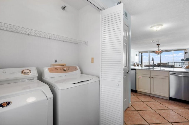 washroom featuring light tile patterned floors, washing machine and dryer, and sink