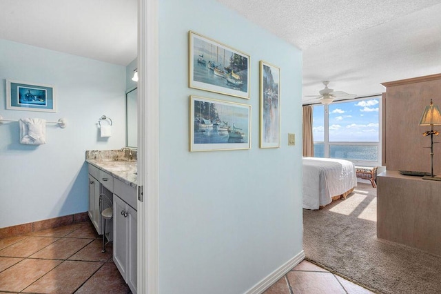 bathroom featuring vanity, tile patterned floors, a water view, ceiling fan, and a textured ceiling