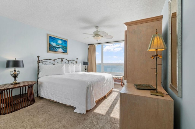 carpeted bedroom featuring ceiling fan, floor to ceiling windows, a water view, and a textured ceiling