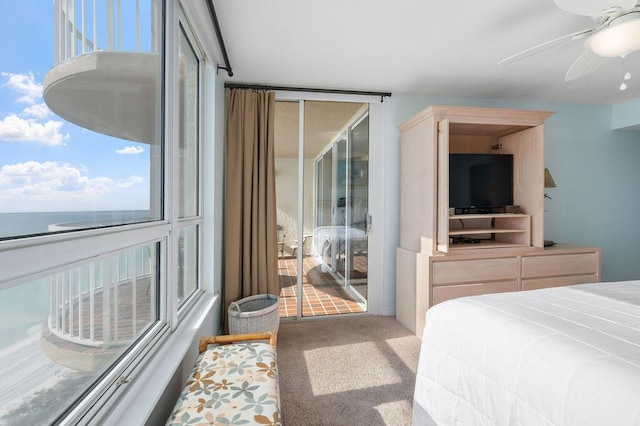 carpeted bedroom with access to outside, multiple windows, ceiling fan, and a water view