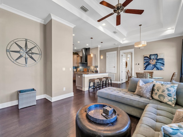 living room featuring dark hardwood / wood-style floors, ceiling fan, a raised ceiling, and crown molding