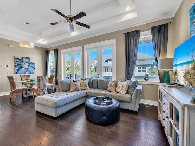 living room featuring a raised ceiling, a wealth of natural light, ceiling fan, and dark hardwood / wood-style floors