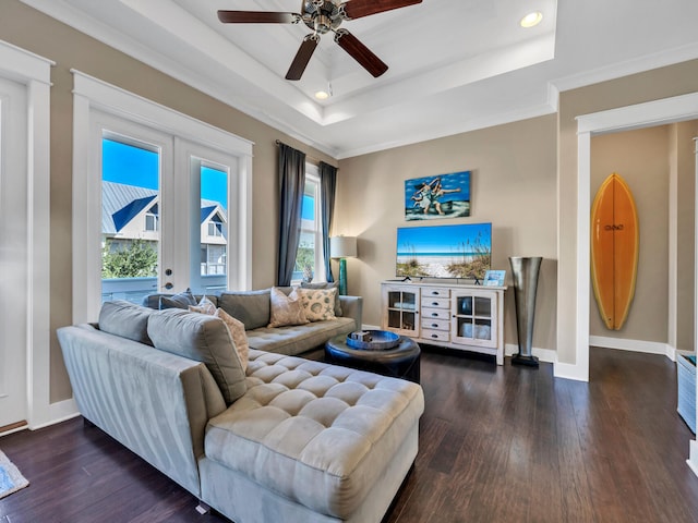 living room featuring dark hardwood / wood-style floors, ceiling fan, a raised ceiling, and plenty of natural light