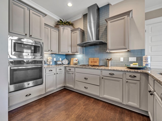 kitchen with wall chimney exhaust hood, stainless steel appliances, light stone counters, gray cabinets, and decorative backsplash