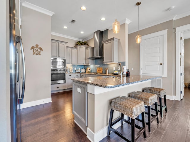 kitchen with appliances with stainless steel finishes, ornamental molding, wall chimney exhaust hood, gray cabinetry, and sink