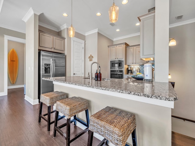 kitchen featuring pendant lighting, a breakfast bar, sink, light stone counters, and stainless steel appliances